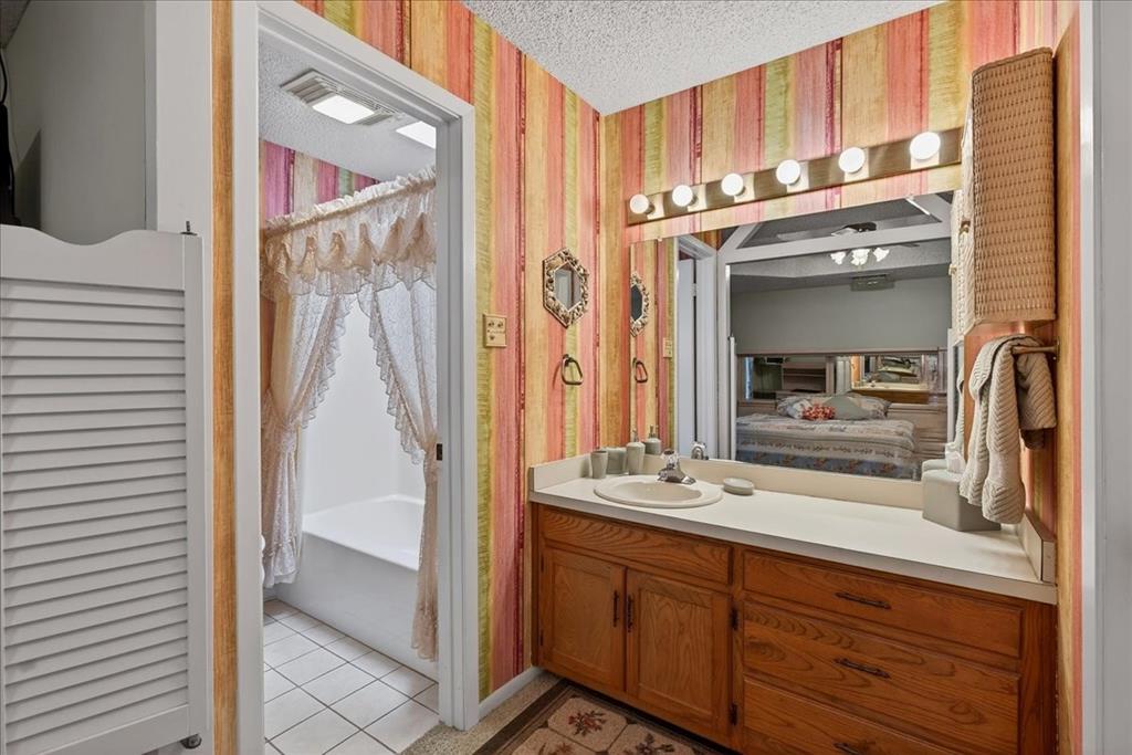 Bathroom vanity featuring a solid surface countertop, integrated sink basin, and wood-finish cabinetry, complemented by a large wall-mounted mirror and multi-bulb fixture