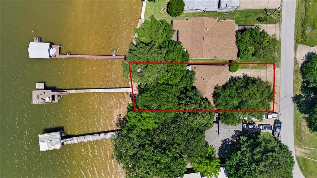 Aerial perspective of waterfront property featuring a private boat dock, extensive shoreline frontage, and mature tree canopy