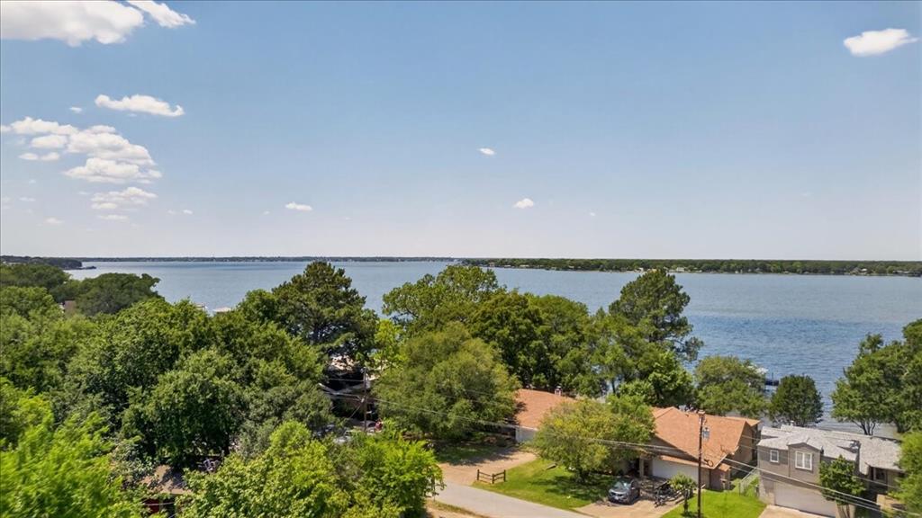 Waterfront property featuring extensive shoreline, mature trees, and paved driveway access