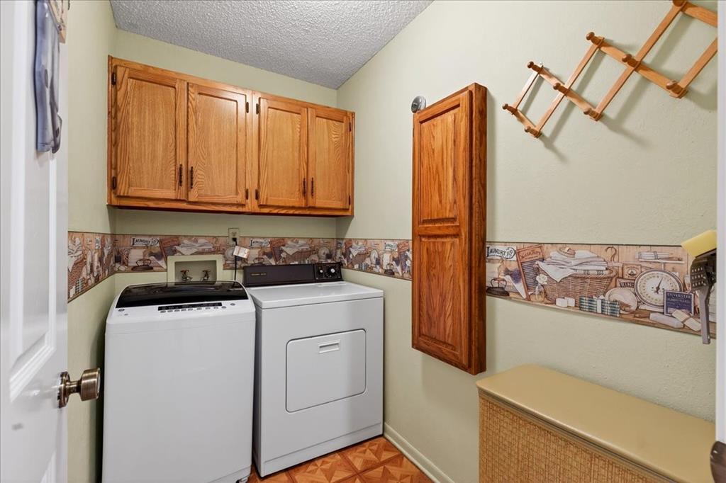 Laundry room featuring upper wood-finish cabinetry, a vertical wall-mounted wood-finish cabinet, and patterned wall border detail