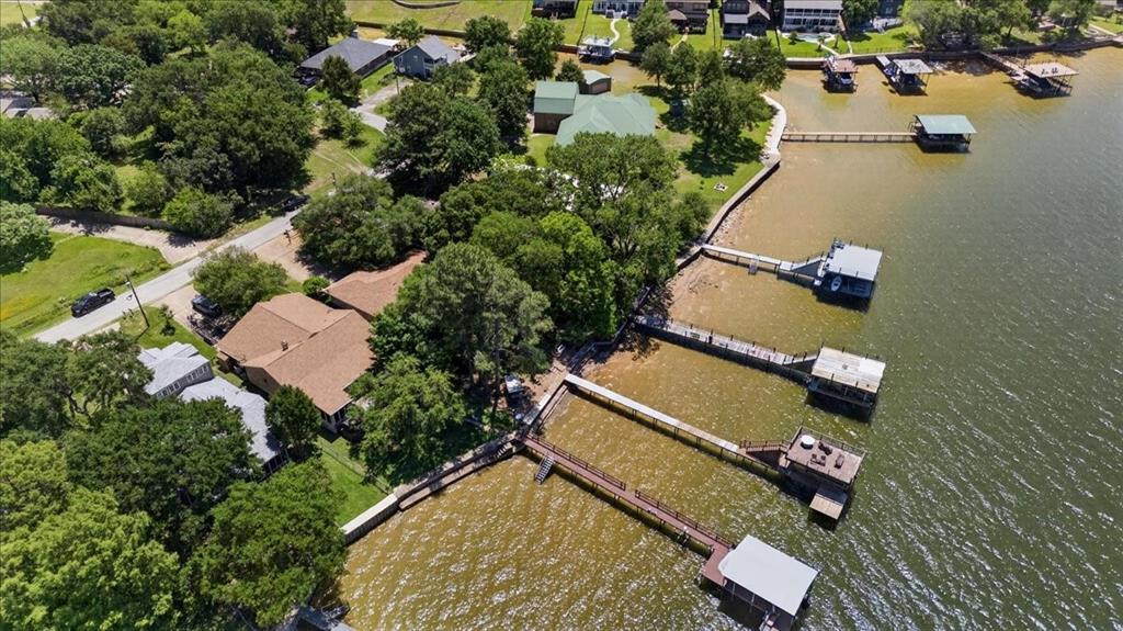 Waterfront property featuring a private boat dock, extensive shoreline, mature trees, and shingle-roof residence