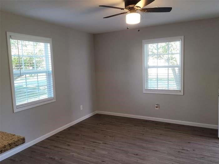 Room featuring wood-finish flooring, dual windows with fitted blinds, and a ceiling-mounted light fixture