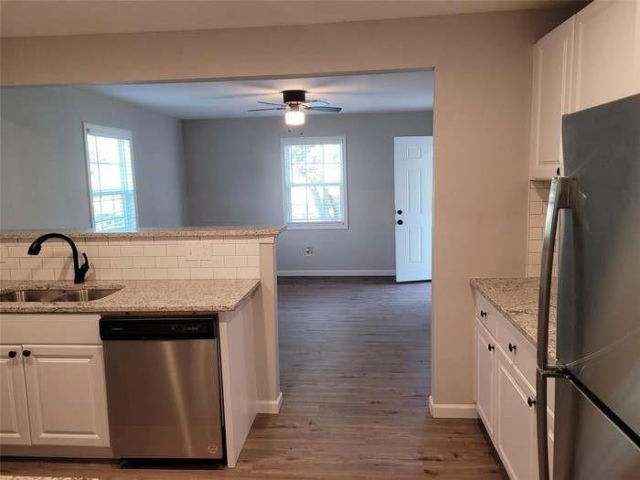 Kitchen featuring white shaker cabinetry, stone-patterned countertops, white subway tile backsplash, and stainless steel appliances