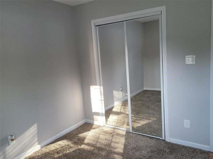 Room featuring neutral wall paint, wall-to-wall carpeting, and floor-to-ceiling sliding mirror closet doors