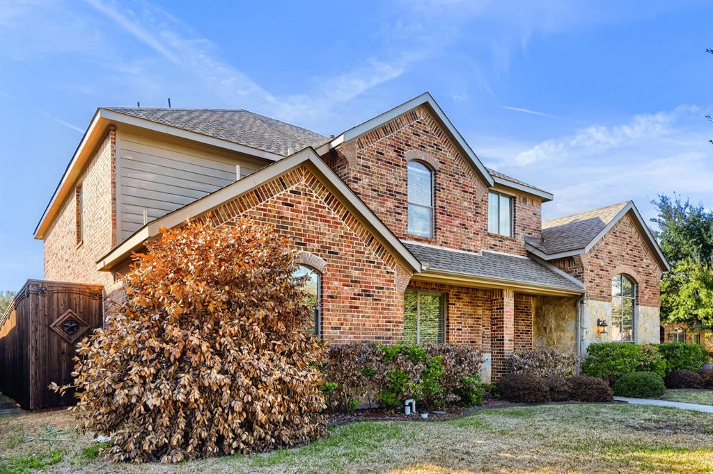 Two-story exterior featuring multi-gabled rooflines, red brick and stone veneer masonry, and arched window detailing