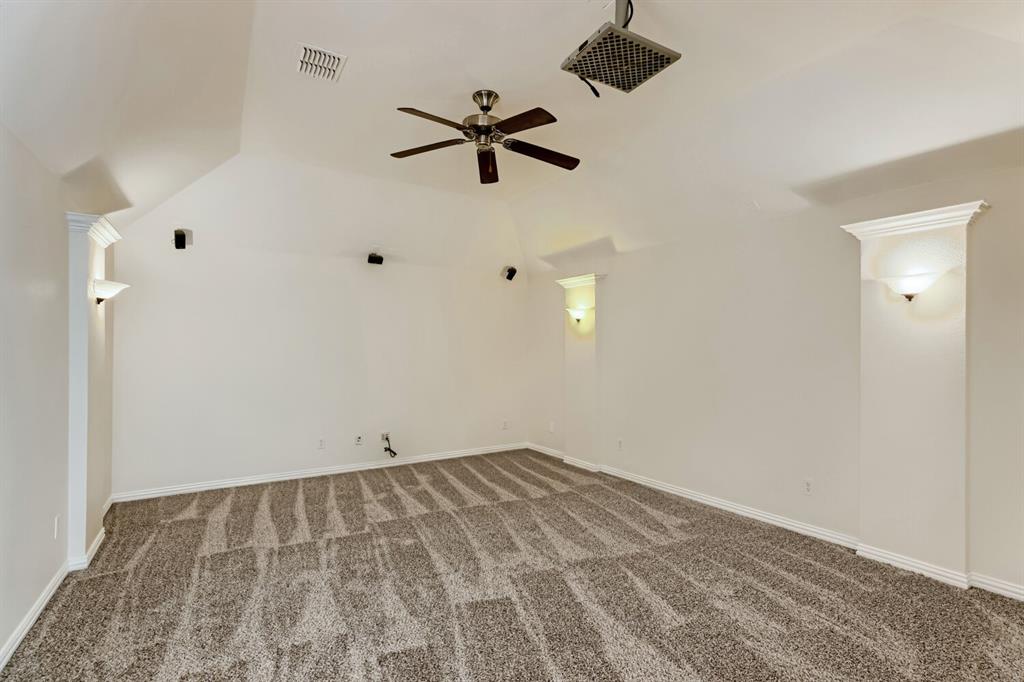 Vaulted ceilings featuring recessed wall niches, integrated wall sconces, carpeted flooring, and a ceiling fan
