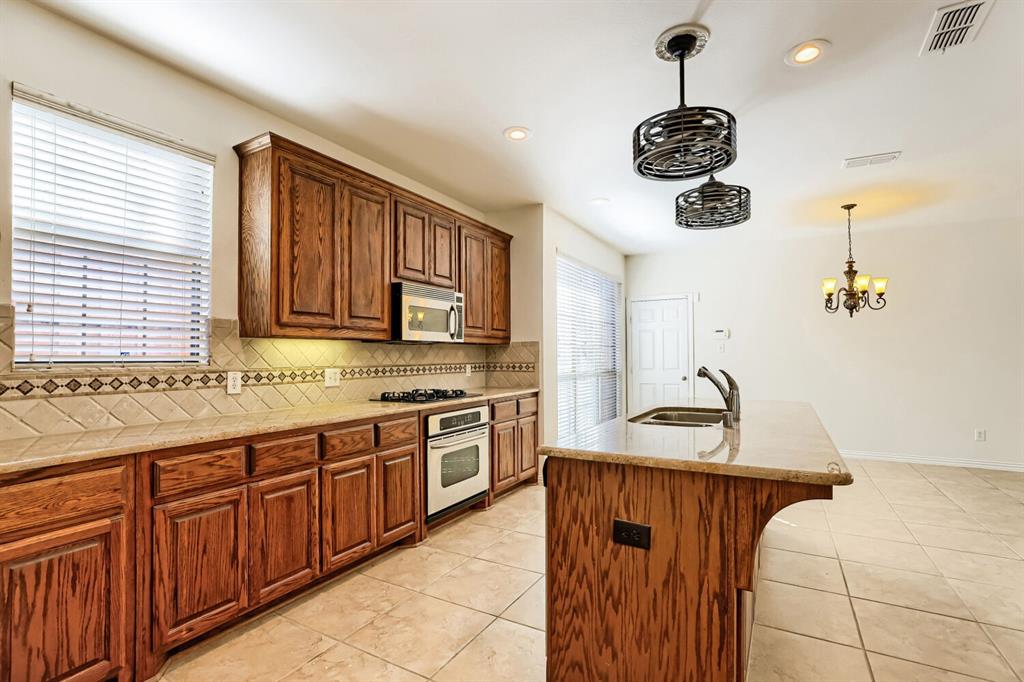 Kitchen featuring wood cabinetry, stone-finish countertops, ceramic tile flooring, a built-in gas cooktop, and decorative tile backsplash