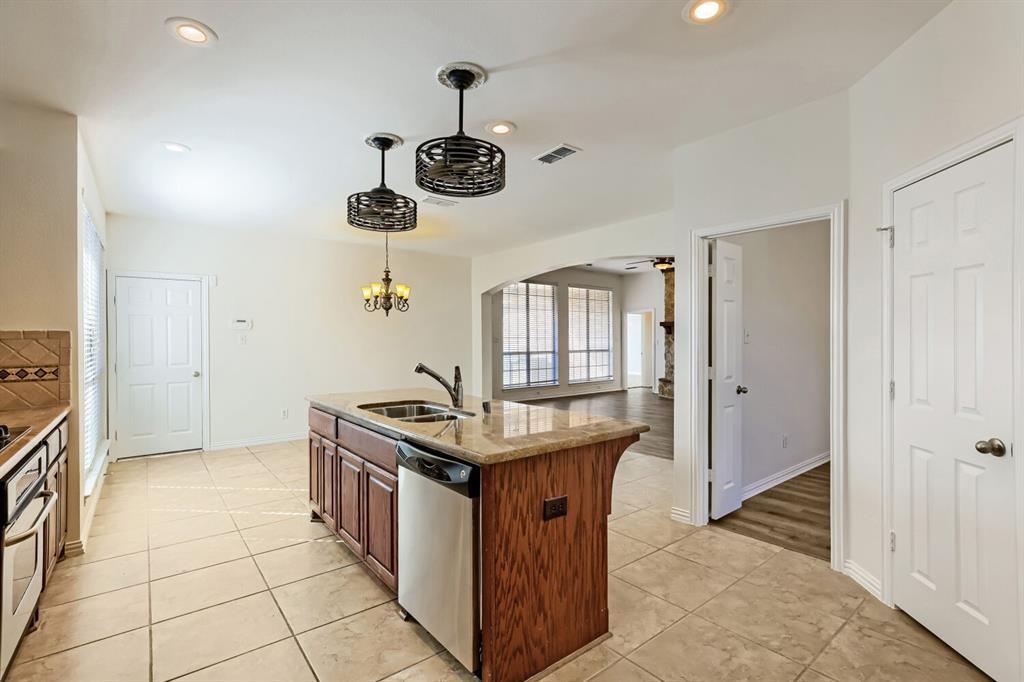 Kitchen island featuring a stone countertop, under-mount stainless steel sink, and wood cabinetry