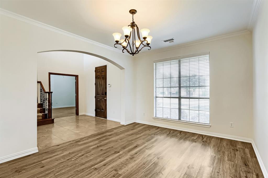 Room featuring wood-finish flooring, a metal multi-light chandelier, an arched architectural opening, and a large multi-pane window