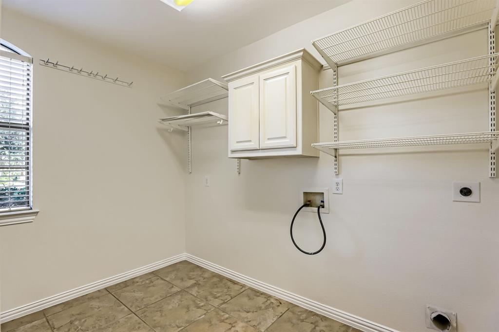 Utility area featuring tile flooring, white shaker-style wall cabinetry, adjustable wire shelving, and an integrated window with horizontal blinds