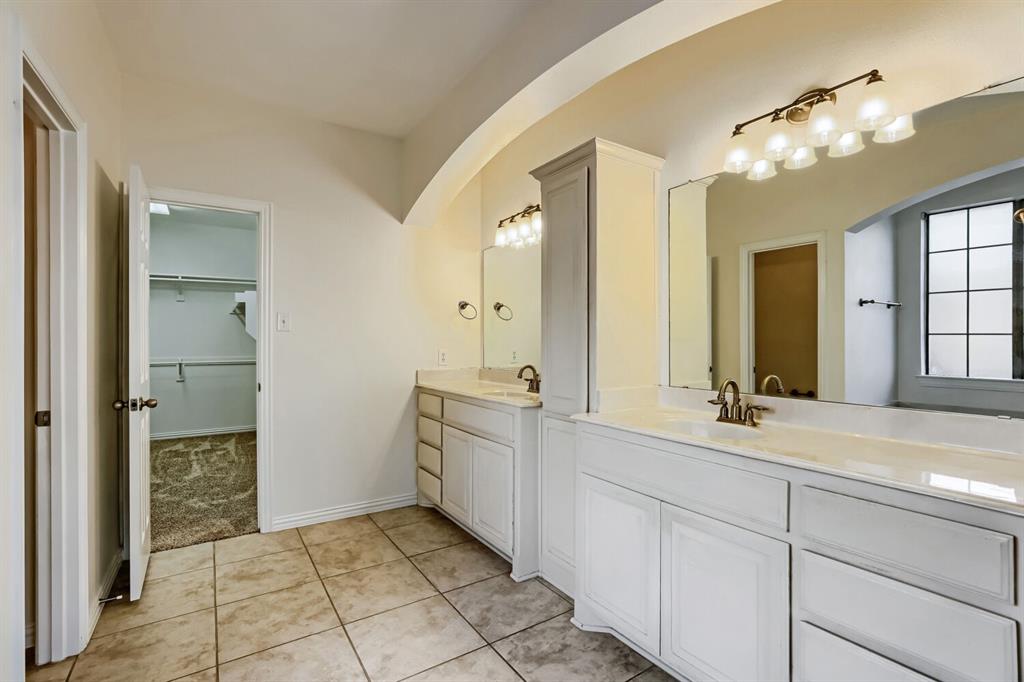 Dual vanity featuring white cabinetry, stone-finish countertops, undermount sinks, and wall-mounted lighting fixtures