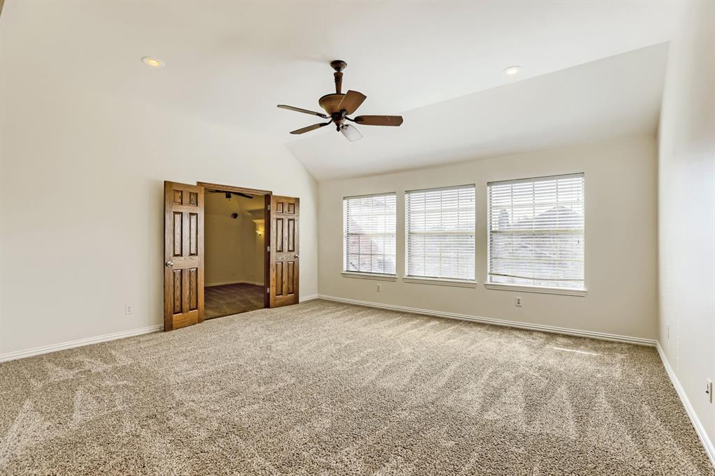 Vaulted ceiling with a centrally mounted ceiling fan, neutral carpeting, three paneled windows, and recessed lighting