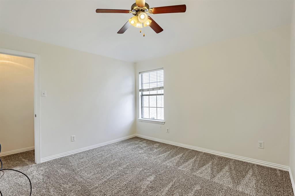 Neutral interior featuring wall-to-wall carpeting, a ceiling fan with integrated lighting, and a window with horizontal blinds