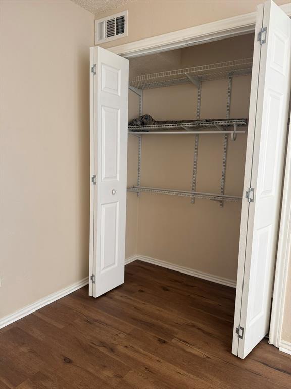 Closet featuring white bi-fold doors and dual-level wire shelving over wood-finish flooring