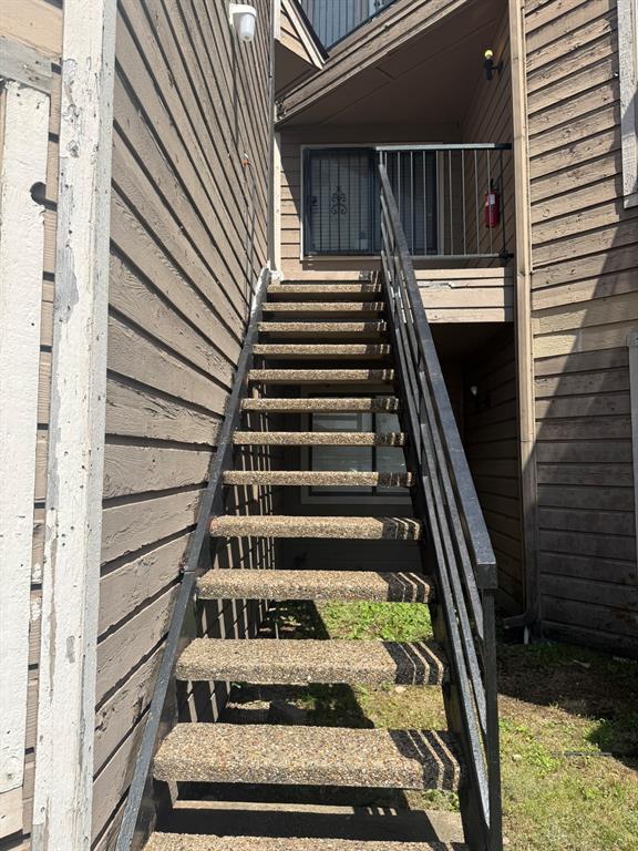 Exterior staircase with aggregate treads, black metal handrails, and lap siding