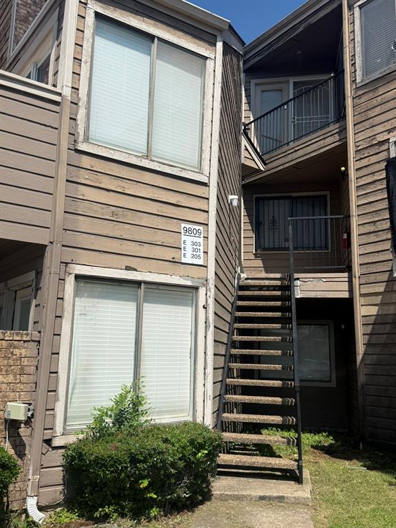 Multi-level residential exterior featuring horizontal siding, external steel staircases, metal railings, and dual-level balconies