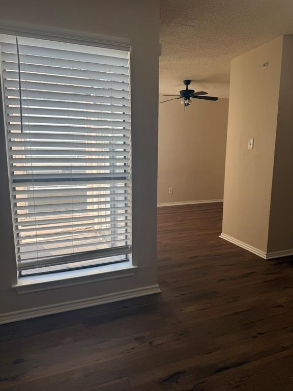 Wood-finish flooring, full-height window with horizontal blinds, and a ceiling-mounted fan with integrated lighting