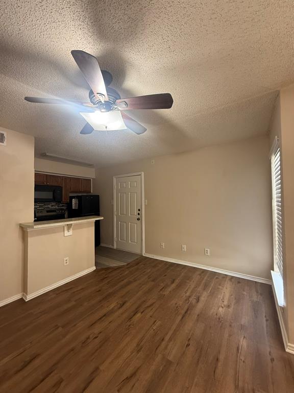 Wood-finish flooring, ceiling fan with integrated lighting, window with horizontal blinds, built-in breakfast bar, and panel-style entry door
