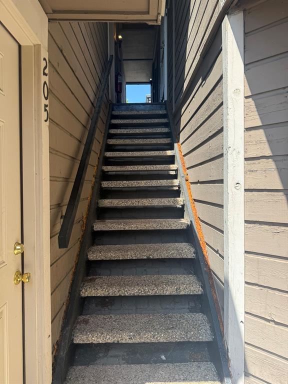 Exterior staircase featuring aggregate treads, horizontal wood-style siding, and a matte-finish handrail