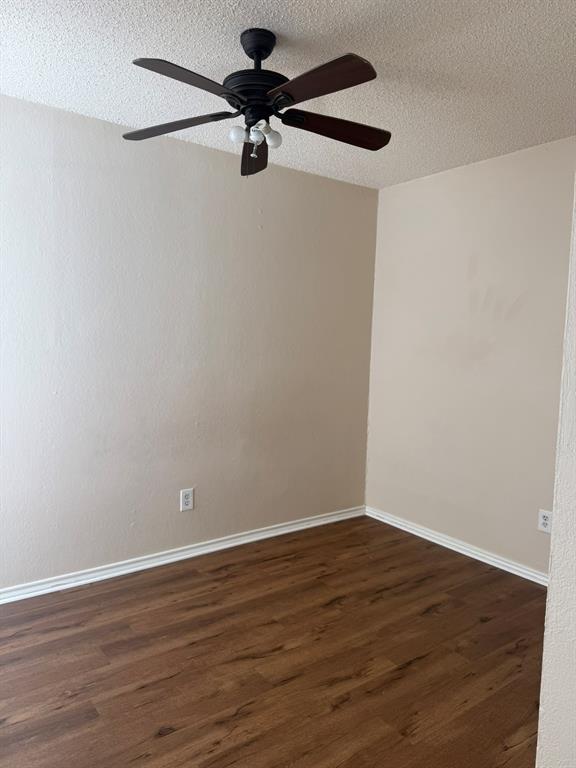 Room featuring wood-finish flooring, textured ceiling, and a dark-toned ceiling fan with integrated lighting