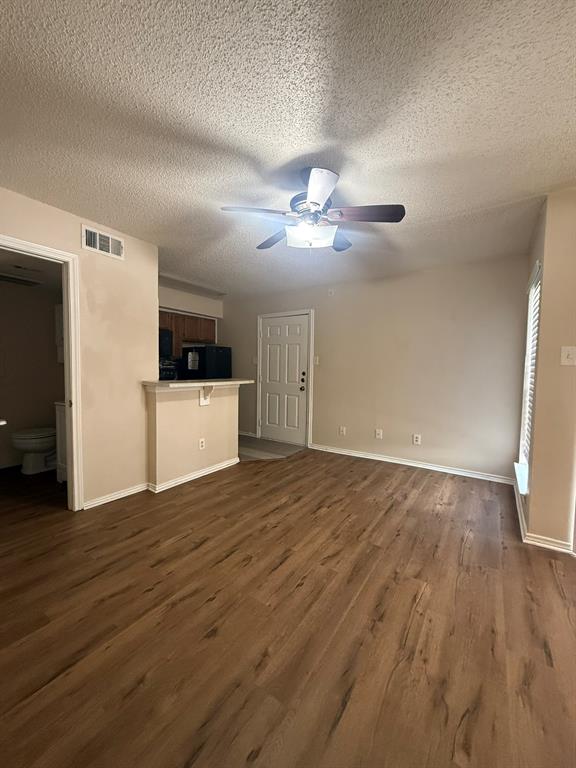 Wood-finish flooring, ceiling fan with integrated lighting, and breakfast bar