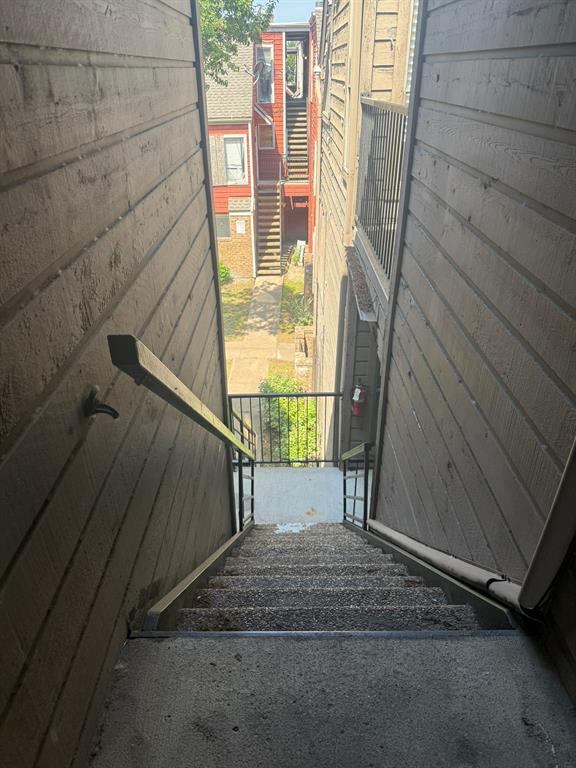 Exterior staircase featuring horizontal siding, metal handrails, and exposed aggregate concrete steps