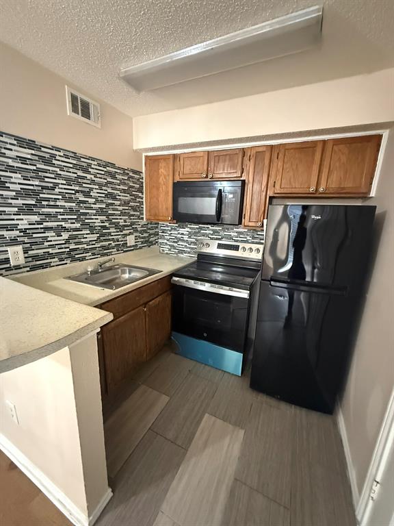Kitchen featuring wood cabinetry, a mosaic tile backsplash, solid-surface countertops, and wood-finish flooring