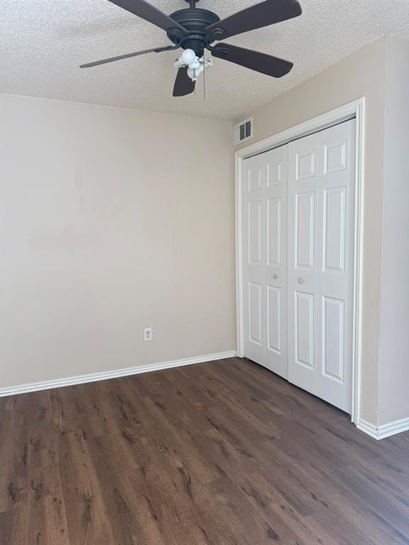 Room featuring wood-finish flooring, a ceiling fan with integrated lighting, and a dual-panel closet door