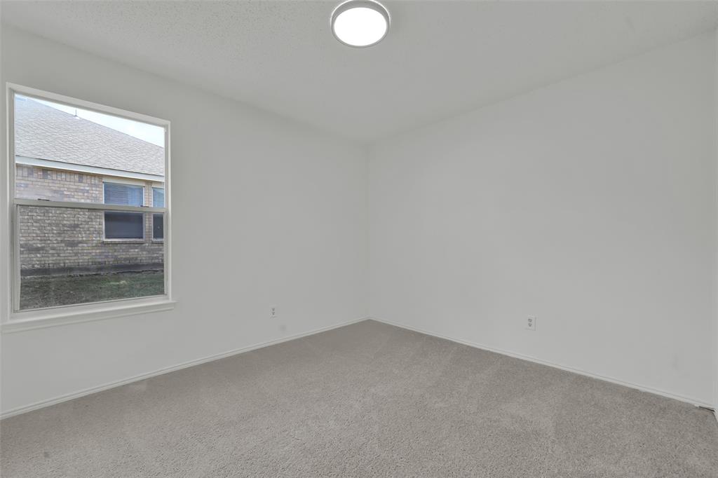 Interior room featuring neutral wall paint, wall-to-wall carpeting, a single-pane window, and a ceiling-mounted flush mount light fixture