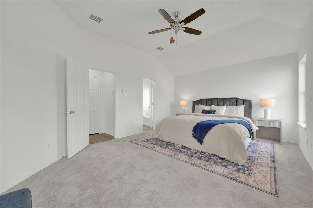 Vaulted ceilings, neutral carpeting, and a ceiling fan with integrated light fixture