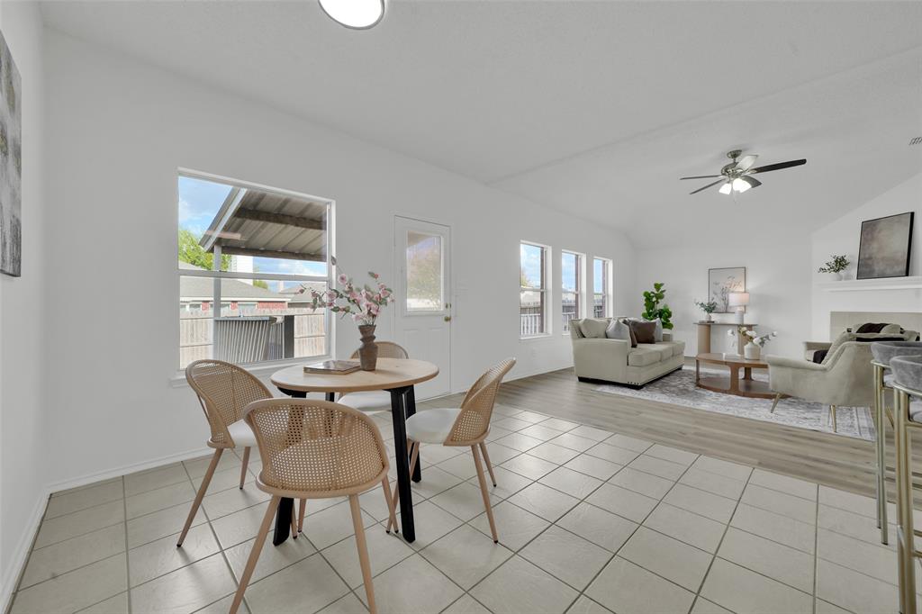 Vaulted ceiling with integrated ceiling fan, ceramic tile flooring, wood-finish flooring, and multiple large windows
