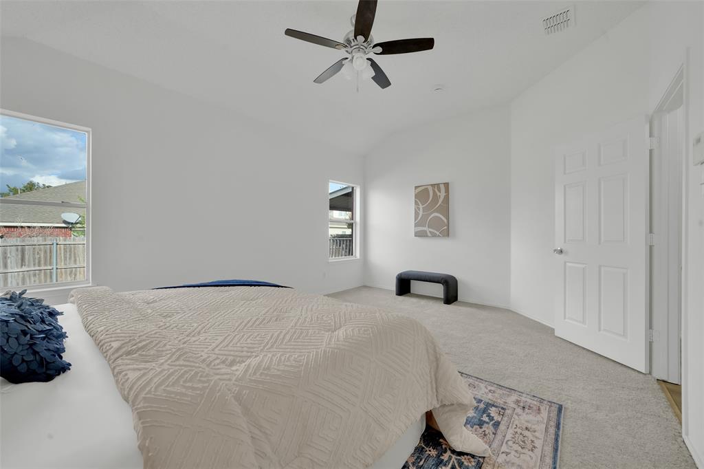 Vaulted ceilings, multi-pane windows, carpeted flooring, and a ceiling fan with integrated lighting
