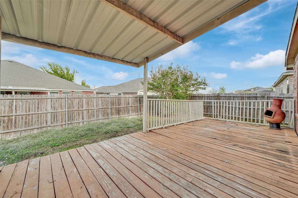 Covered wood deck with metal roofing and a perimeter railing, enclosed by wood privacy fencing