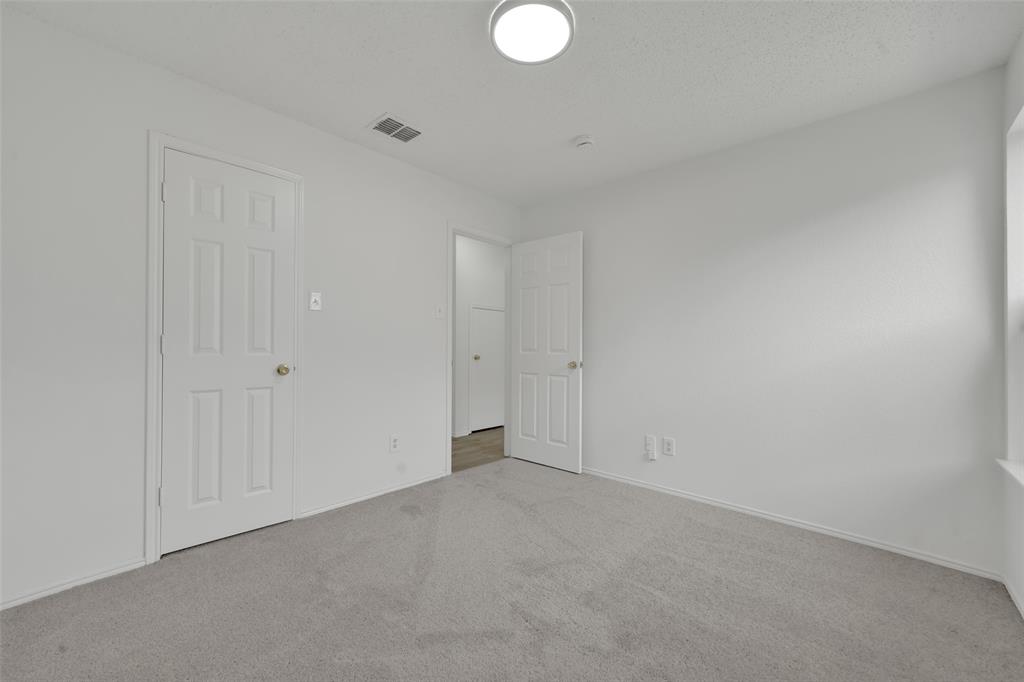 Neutral interior room featuring neutral-tone carpeting, white walls, flush-mount ceiling lighting, and multi-panel interior doors