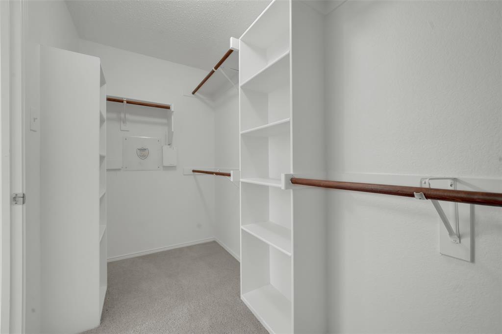 Walk-in closet featuring white built-in shelving towers and multiple wooden hanging rods