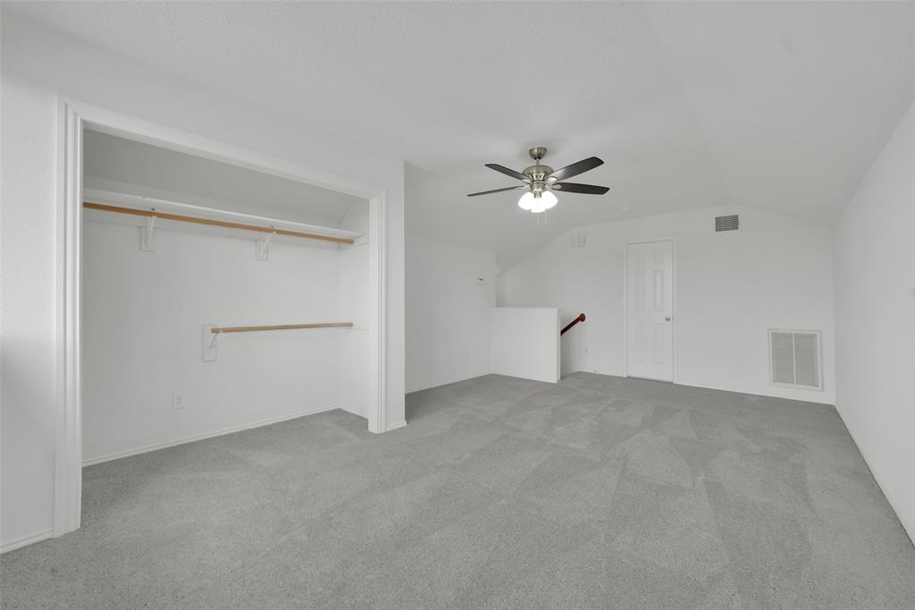 Neutral-toned wall-to-wall carpeting, open-concept closet with dual tiered hanging rods, multi-blade ceiling fan with integrated light fixture, and six-panel interior door