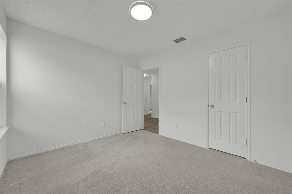 Neutral-toned carpeting, crisp white walls, flush-mount dome lighting, and six-panel interior doors