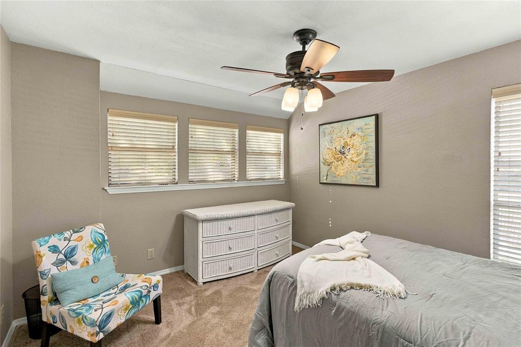 Neutral-toned interior featuring triple-window configuration, carpeted flooring, and a ceiling fan with integrated light fixture