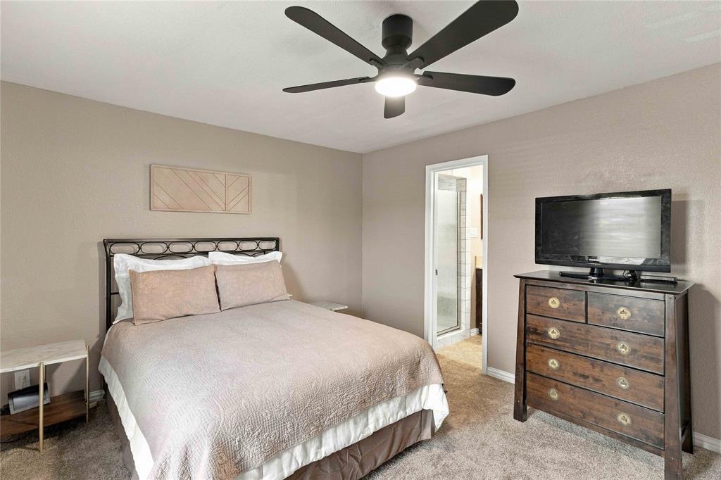 Neutral wall-toned room featuring a central five-blade matte black ceiling fan with an integrated light fixture and neutral carpeting