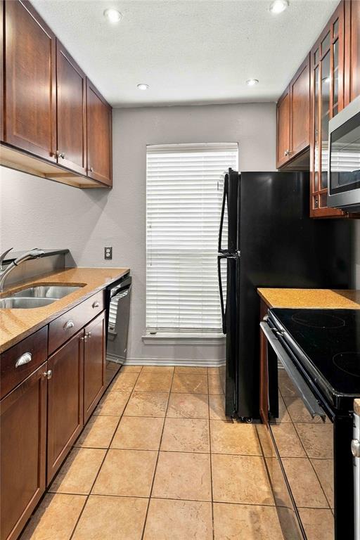 Kitchen featuring wood cabinetry, stone-finish countertops, ceramic tile flooring, built-in stainless steel appliances, and recessed ceiling lighting