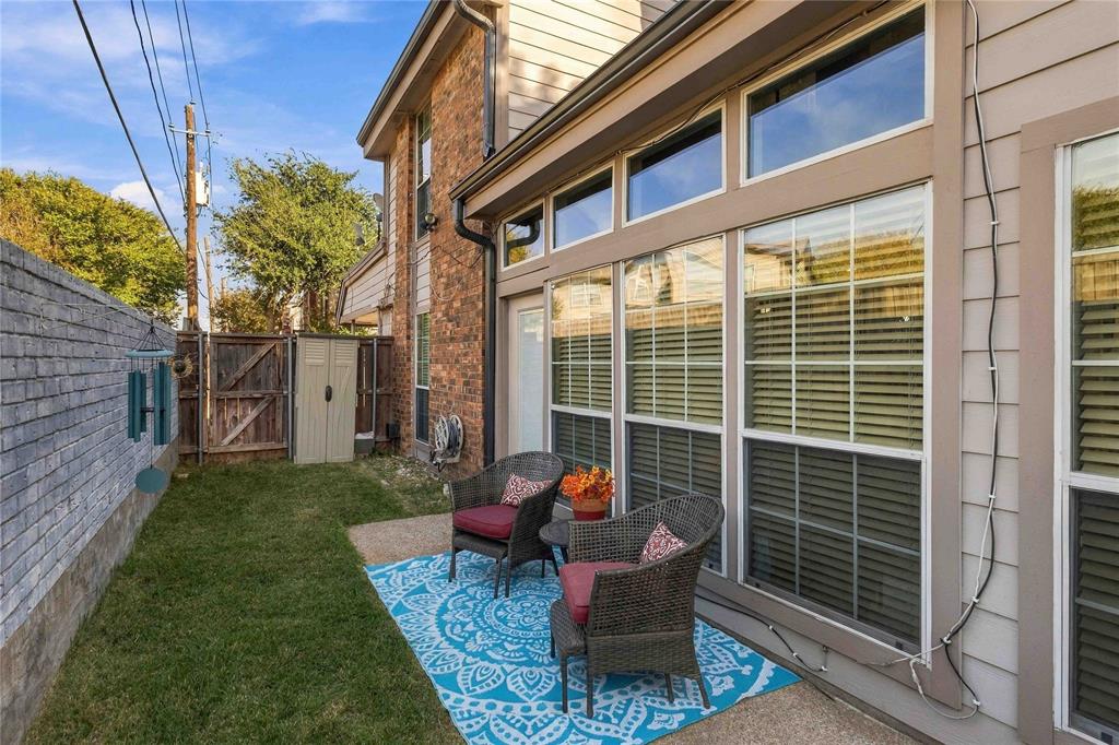 Exterior features include a concrete patio, brick and horizontal siding facade, expansive multi-pane windows, and a privacy wall