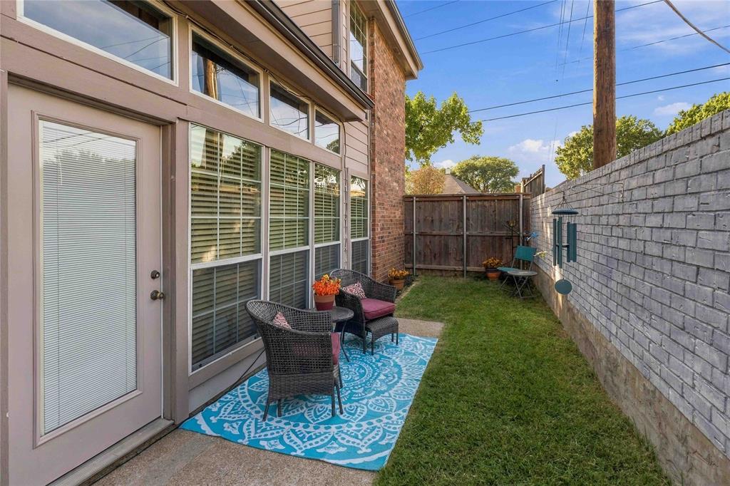 Exterior space featuring a concrete patio, a private lawn, a wood fence, and a painted brick privacy wall