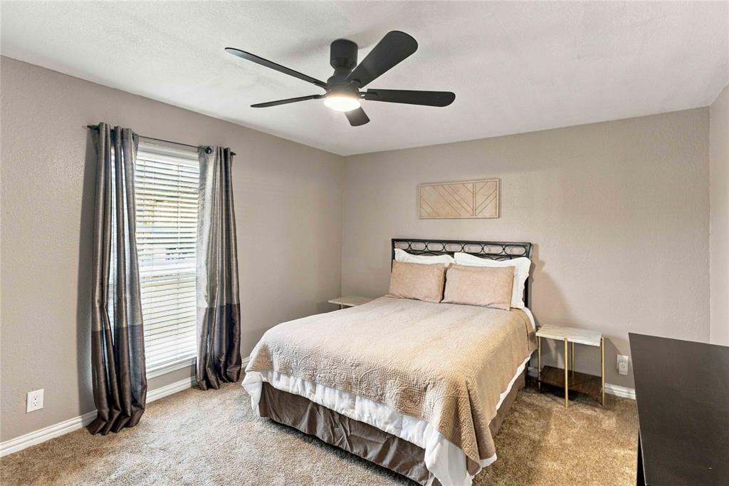 Neutral-toned interior space featuring wall-to-wall carpeting and a matte black five-blade ceiling fan with integrated lighting