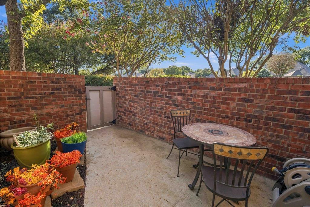 Enclosed outdoor patio featuring a concrete floor, red brick perimeter walls, and a hinged privacy gate