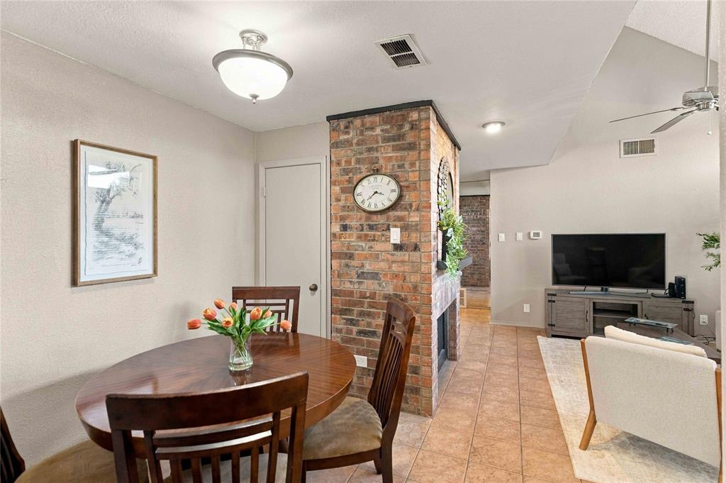 Exposed brick dual-sided fireplace, vaulted ceiling with integrated ceiling fan, and ceramic tile flooring