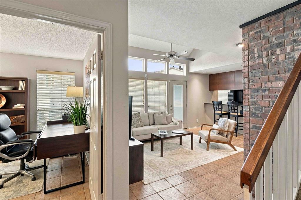 Interior featuring vaulted ceilings, a brick-faced accent wall, tile flooring, and multi-pane windows