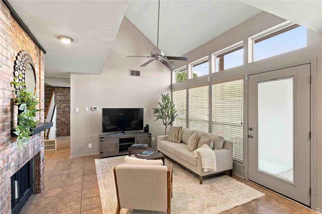 Vaulted ceilings, floor-to-ceiling brick fireplace with wood-finish mantle, ceramic tile flooring, and oversized windows with transom accents