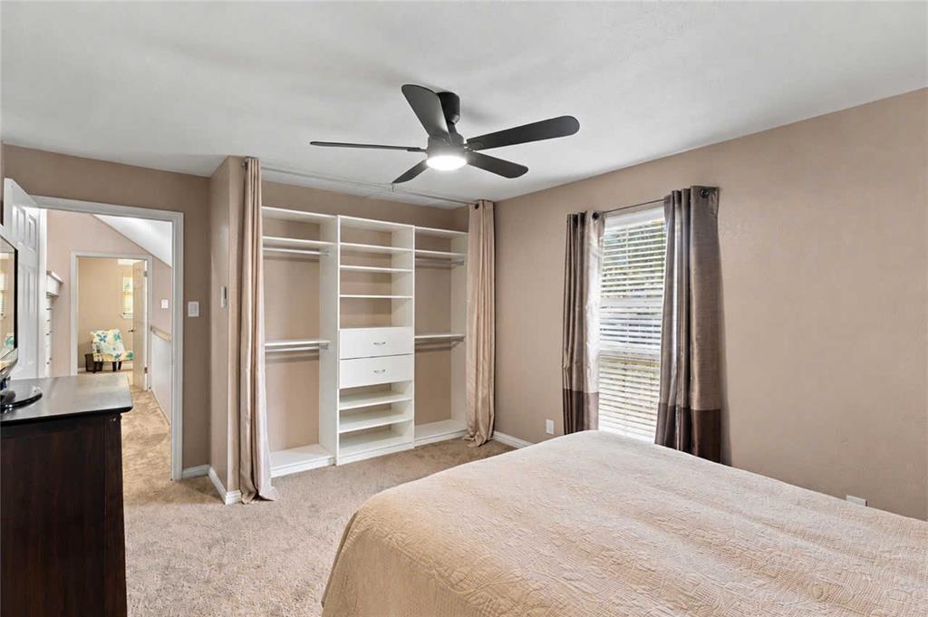 Room featuring a built-in closet system with integrated shelving and drawers, a ceiling fan with integrated lighting, wall-to-wall carpeting, and a window with blinds