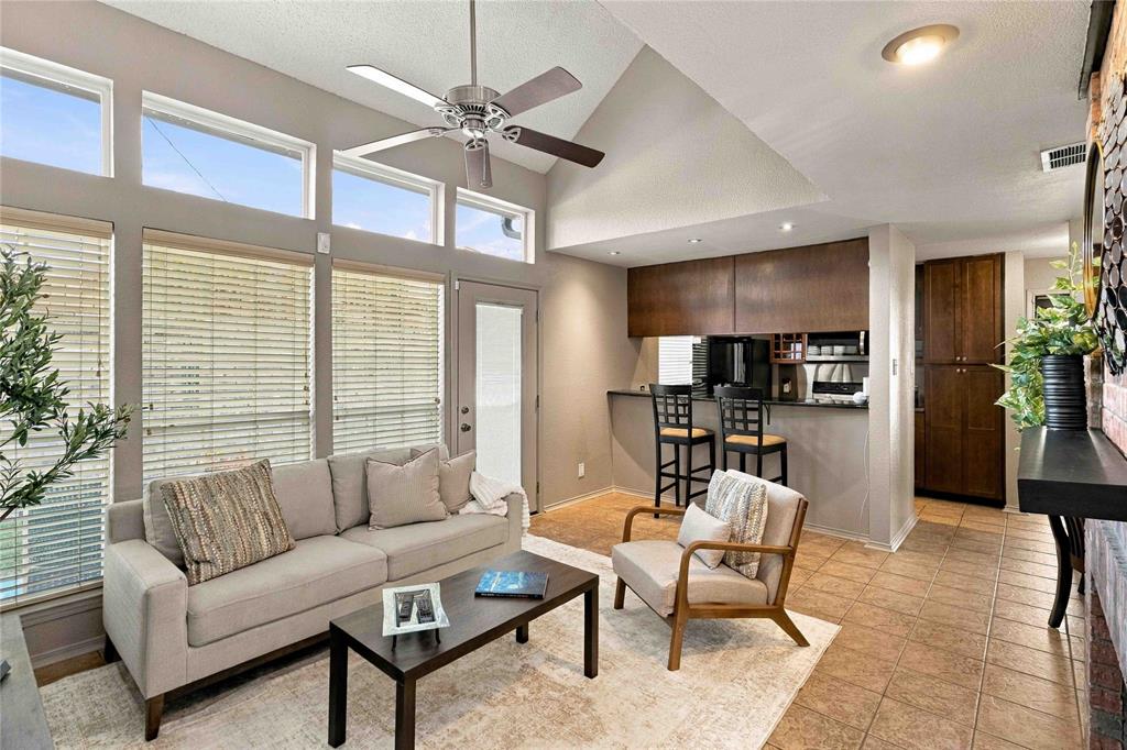 Vaulted ceilings with a ceiling fan, expansive transom windows, ceramic tile flooring, built-in floor-to-ceiling cabinetry, and a kitchen pass-through counter