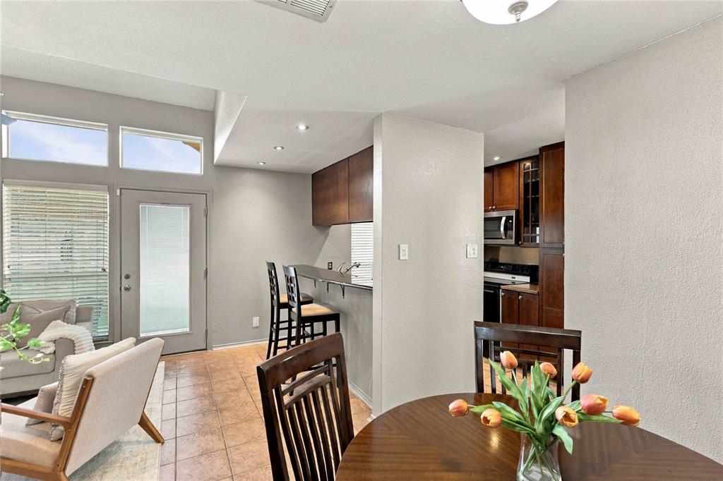 Kitchen featuring a built-in breakfast bar, dark-finish cabinetry, built-in microwave, tile flooring, and high-reaching ceilings with transom windows